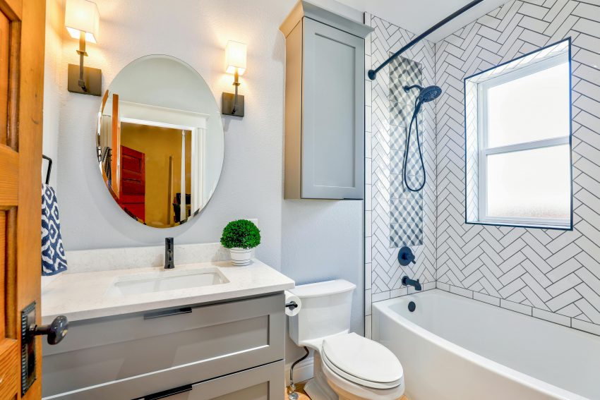 small bathroom with a mirrored vanity, a toilet, and a bathtub-shower combo