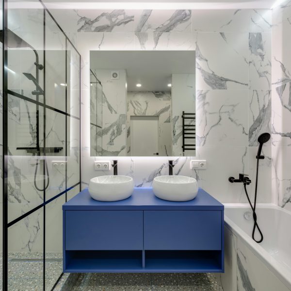 marble bathroom with a blue double-sink vanity and bathtub